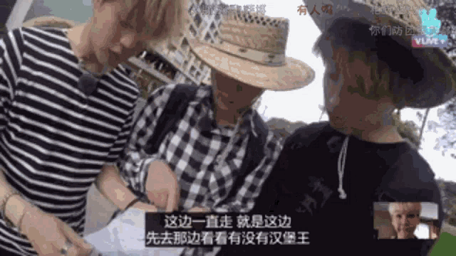three men wearing straw hats and plaid shirts are looking at something