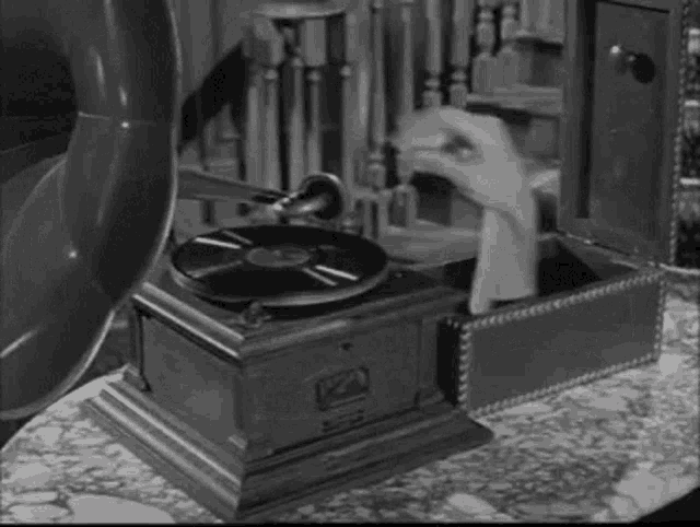 a black and white photo of a person playing a record on a gramophone .