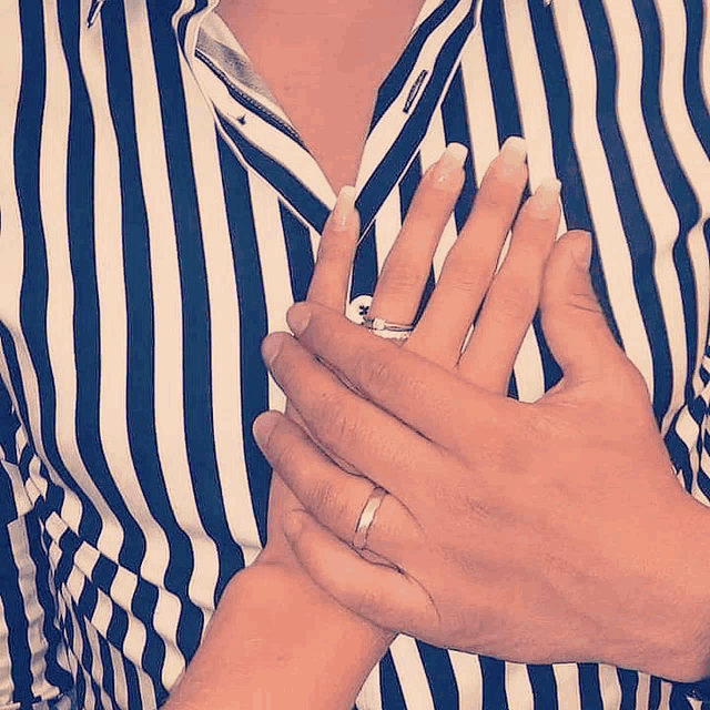 a man wearing a striped shirt is holding a woman 's hand