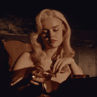 a woman in a black dress holds a glass of wine