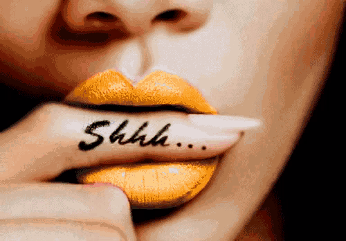 a close up of a woman 's mouth with yellow lipstick and the word shh written on her finger