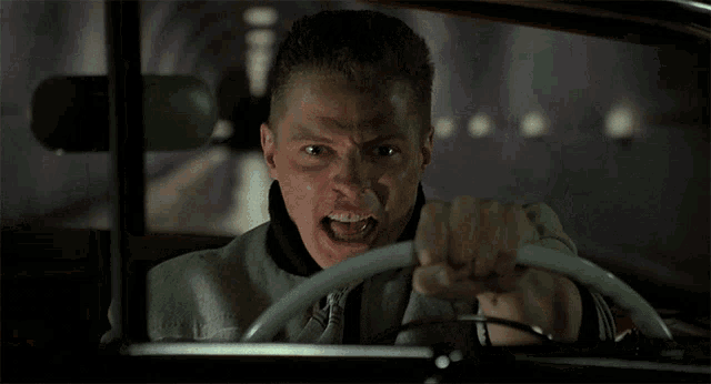 a man driving a car with his mouth open and his teeth showing
