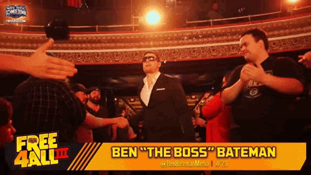a man in a suit and sunglasses stands in front of a crowd with the name ben " the boss " bateman on the screen