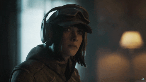 a woman wearing a helmet and goggles holds her finger to her mouth