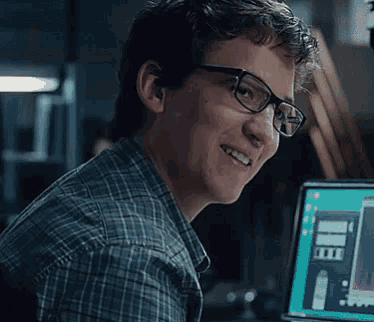 a man with glasses is smiling in front of a computer screen