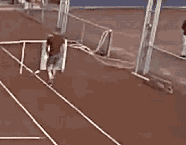 a man is walking down a track with a fence in the background