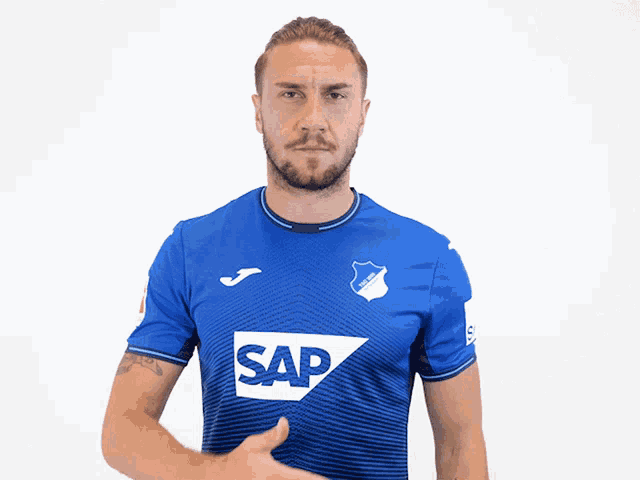 a man in a blue tsg shirt holds his hands to his chest