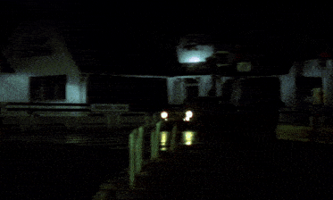 a car is driving down a street at night under green lights