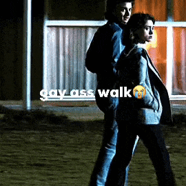 a man and a woman are walking in front of a building with the words gay ass walk written above them