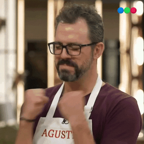 a man wearing glasses and an apron with the name agust on it