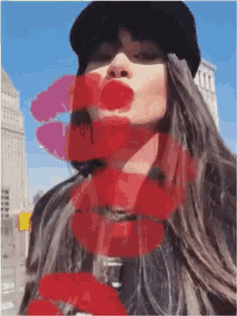 a woman wearing a hat and holding a red flower has a kiss on her lips