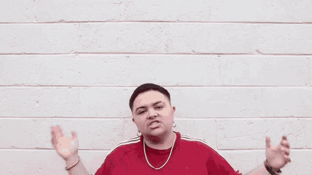 a man wearing a red adidas shirt is standing in front of a white wall