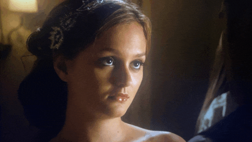 a woman with a tiara on her head looks at a man