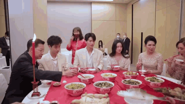 a group of people sitting at a table with bowls of food
