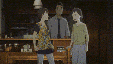 a man and two women standing in a living room with a cat in the background