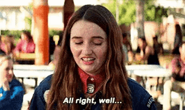 a girl is standing in front of a crowd with her eyes closed and saying `` all right , well . ''
