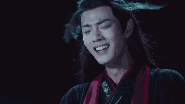 a man with long hair and a red scarf laughs
