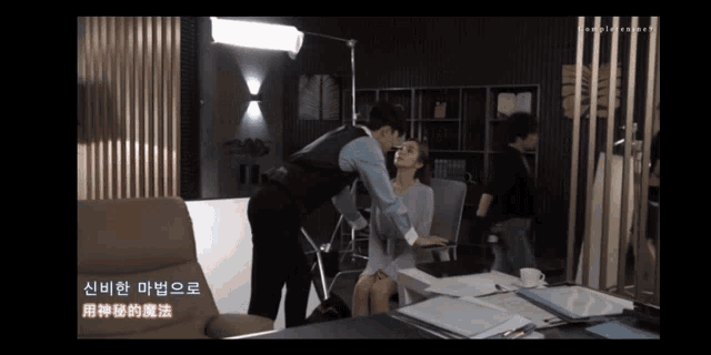 a man kisses a woman on the cheek in a room with chinese writing on the bottom