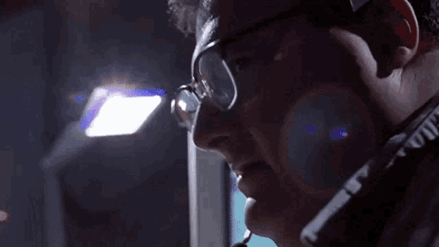 a man wearing glasses and a headset is looking down