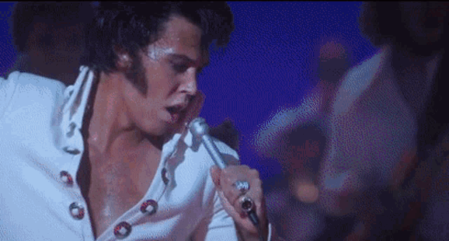 a man is singing into a microphone with a ring on his finger