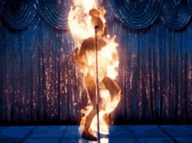 a naked man is on fire while standing in front of a microphone