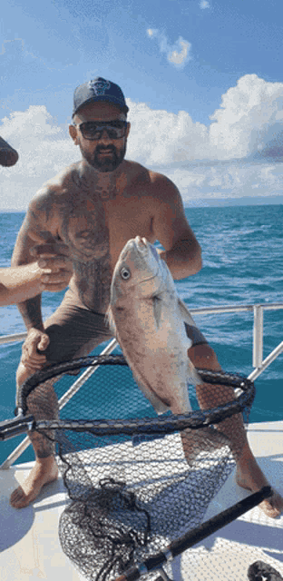 a man on a boat holding a fish in a net