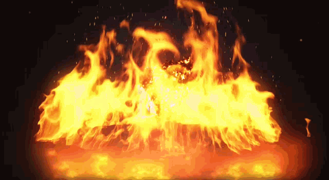 a large fire with sparks coming out of it in the dark