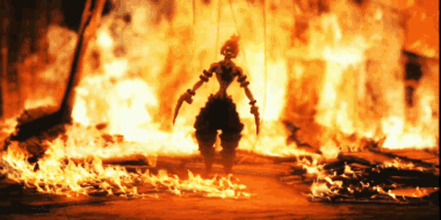 a silhouette of a person standing in front of a large fire