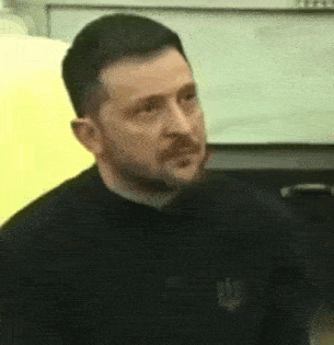 a man with a beard is wearing a black shirt and making a face .
