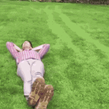 a woman is laying in the grass next to a pink car .