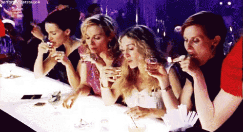 a group of women are sitting at a bar drinking wine
