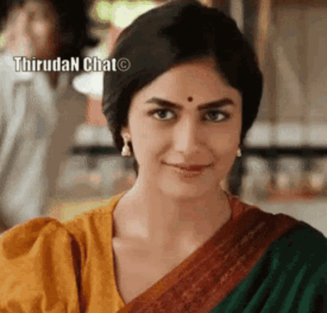 a close up of a woman wearing a yellow and green saree and smiling .