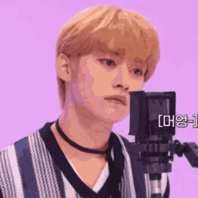 a young man is standing in front of a microphone with a choker around his neck .
