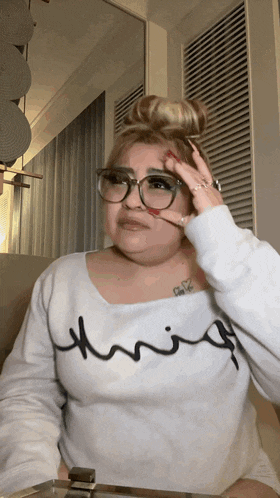 a woman wearing glasses and a white shirt that says thrifty on it