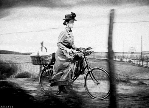 a black and white photo of a woman riding a bike with bellecs written on the bottom right