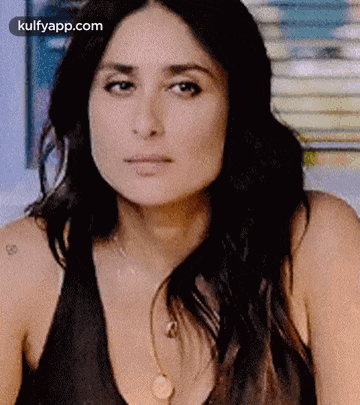 a close up of a woman 's face wearing a black tank top and a necklace .