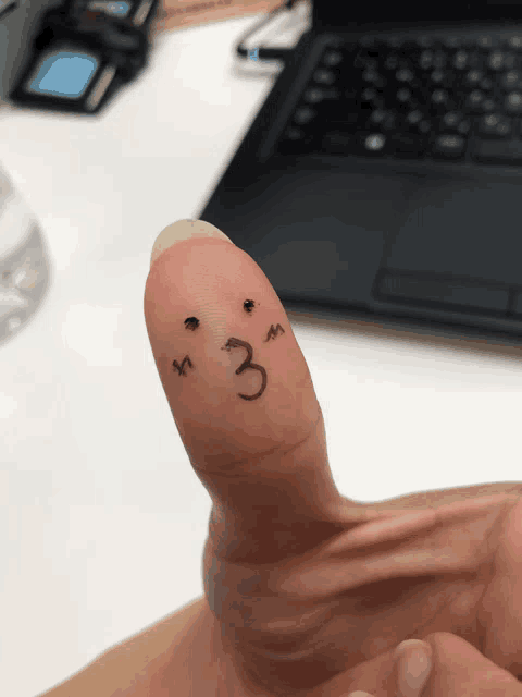 a person 's finger with a face drawn on it and the number 3 on it
