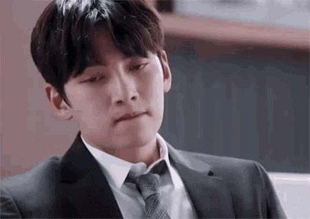 a young man in a suit and tie is making a face .