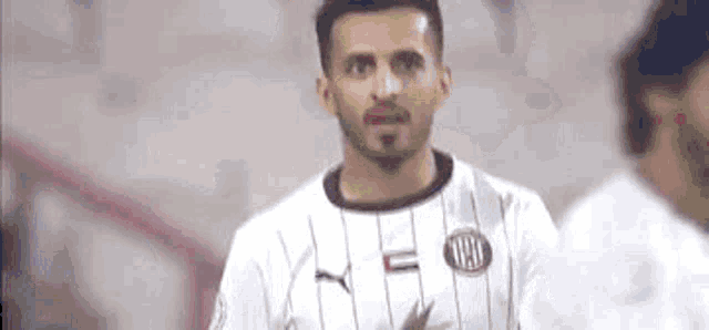 a man with a beard is wearing a white and black striped shirt with the letter y on it .