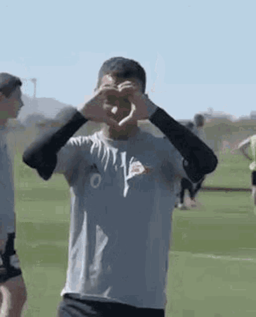 a soccer player is making a heart shape with his hands on a soccer field .