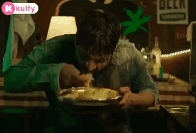 a man is sitting at a table with a plate of food in front of him and a sign that says beer .