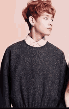 a young man with red hair is wearing a sweater and a white shirt