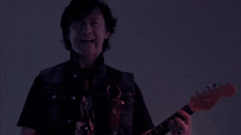 a man playing a guitar in a dark room