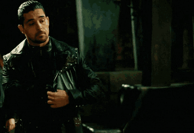 a man in a leather jacket holds a gun
