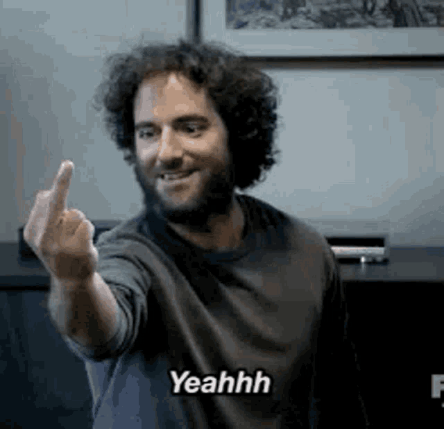 a man with curly hair is giving the middle finger .