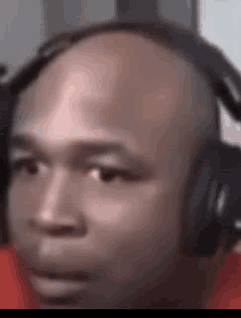 a bald man is wearing headphones and looking at the camera .