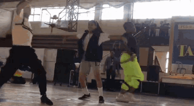 a group of people dancing in a gym with a sign that says ta on it