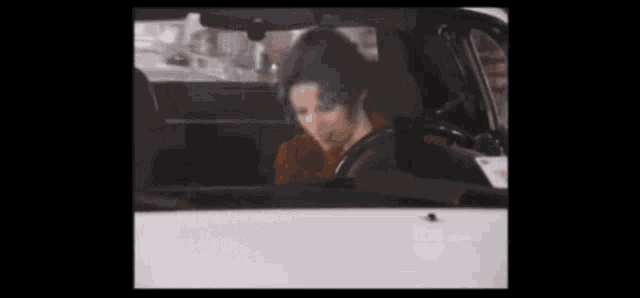 a man in a red shirt is sitting in a car .