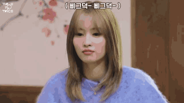 a girl with blonde hair is wearing a purple sweater and necklace .