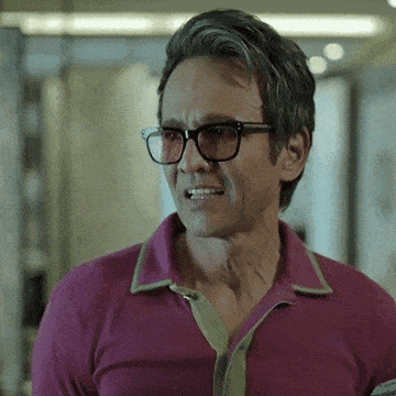 a man wearing glasses and a pink shirt is making a funny face